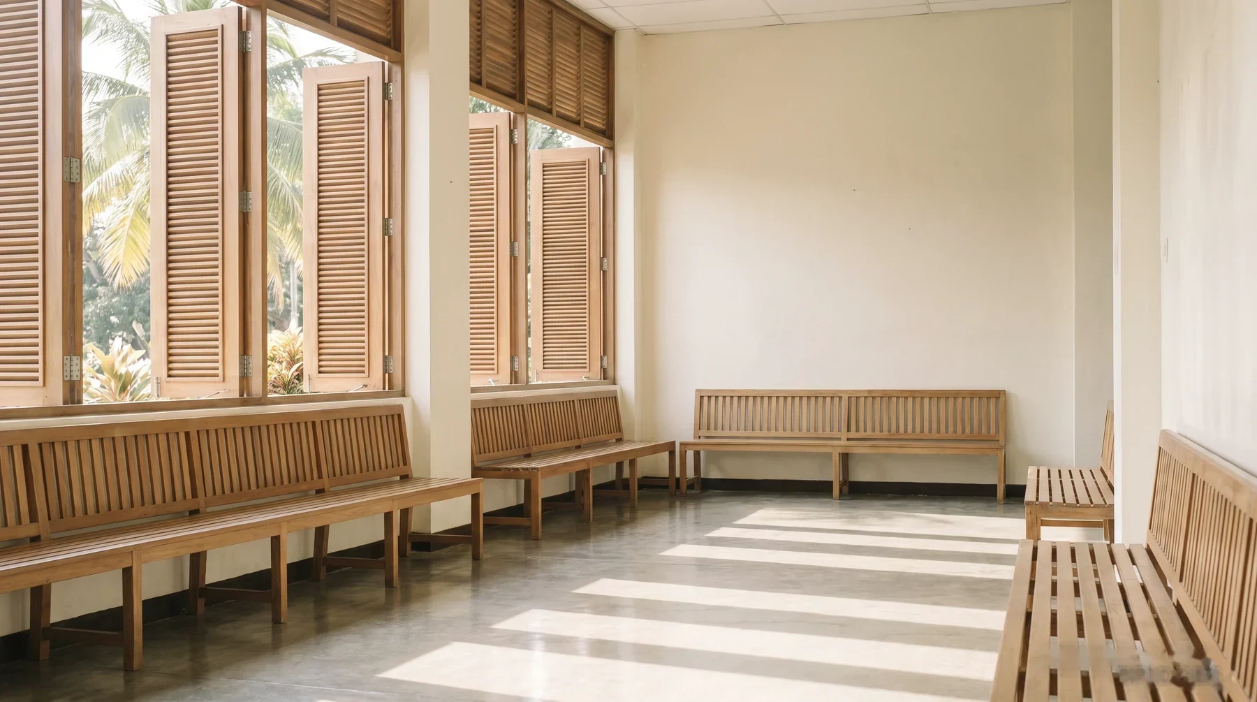 A government office waiting room with wooden benches and tropical light