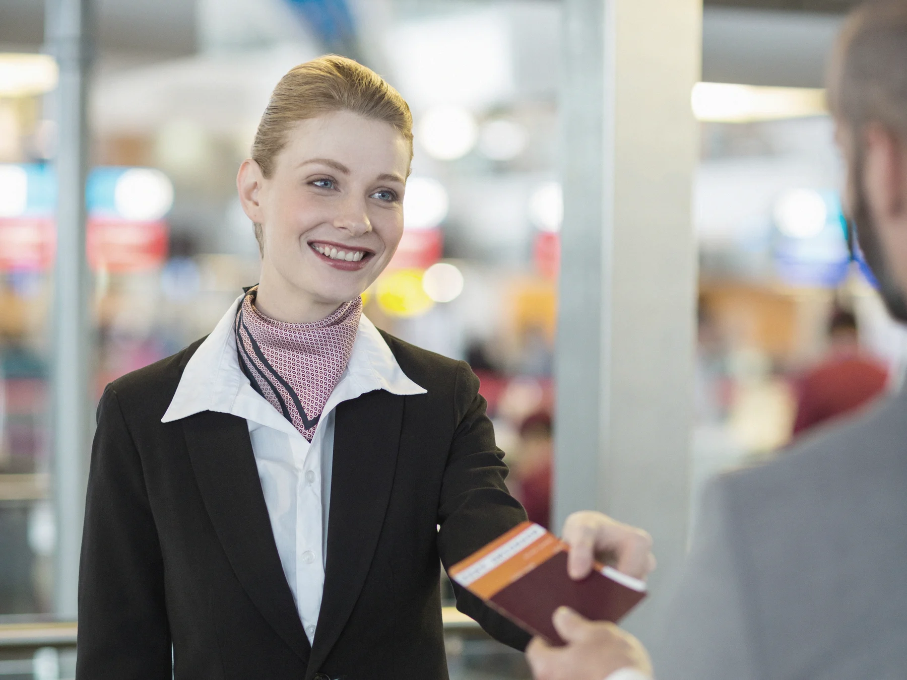An airline agent checks a passenger's passport at the check-in desk