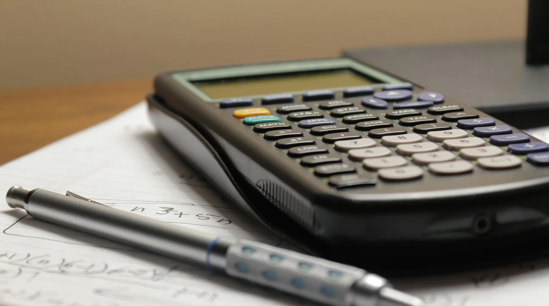 A calculator and a pen on sheets of calculations