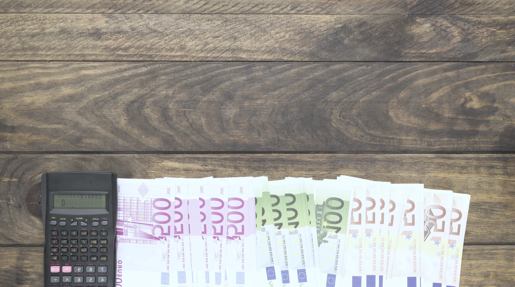 Euro notes and a calculator on a desk: counting money in a foreign account