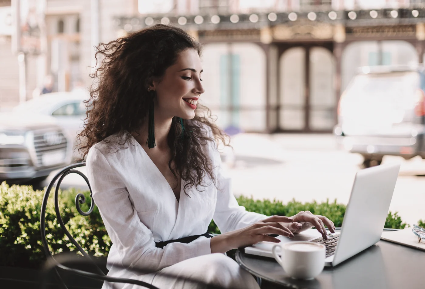 A woman working on a laptop at a street cafe