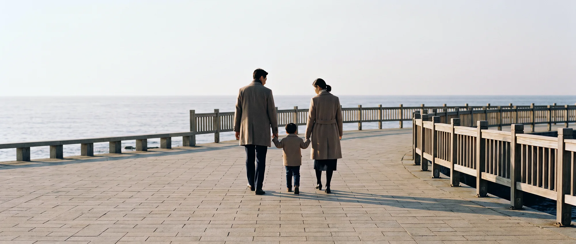 A family with a child walking along a promenade, seen from behind